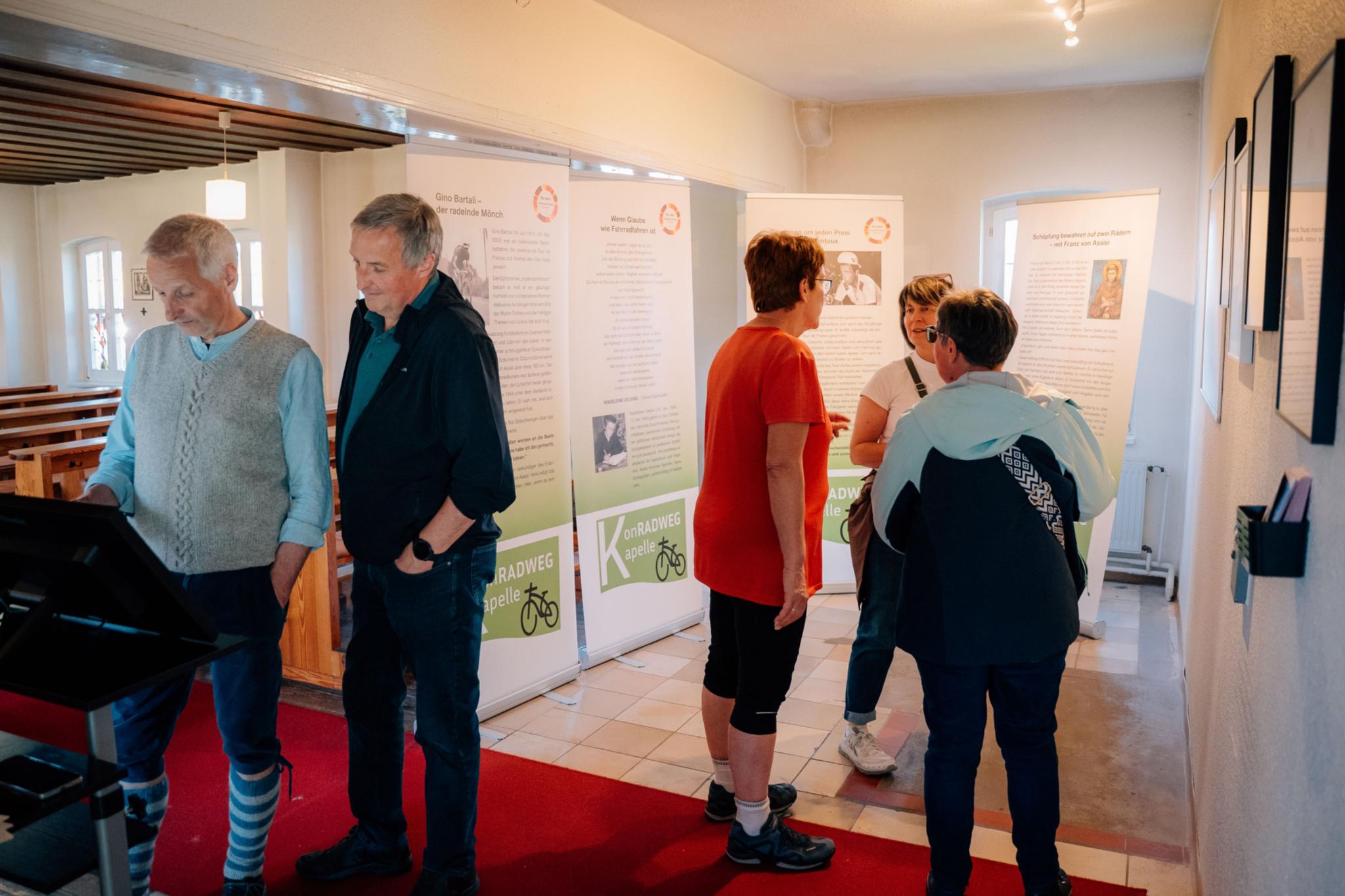 Gläubige informieren sich in einer kleinen Ausstellung über die Verbindung von Glauben zum Radfahren