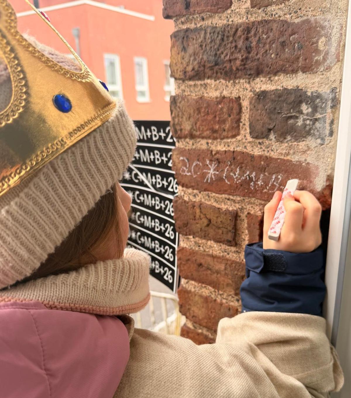 Königin Lenja schreibt den Segenspruch an die Tür