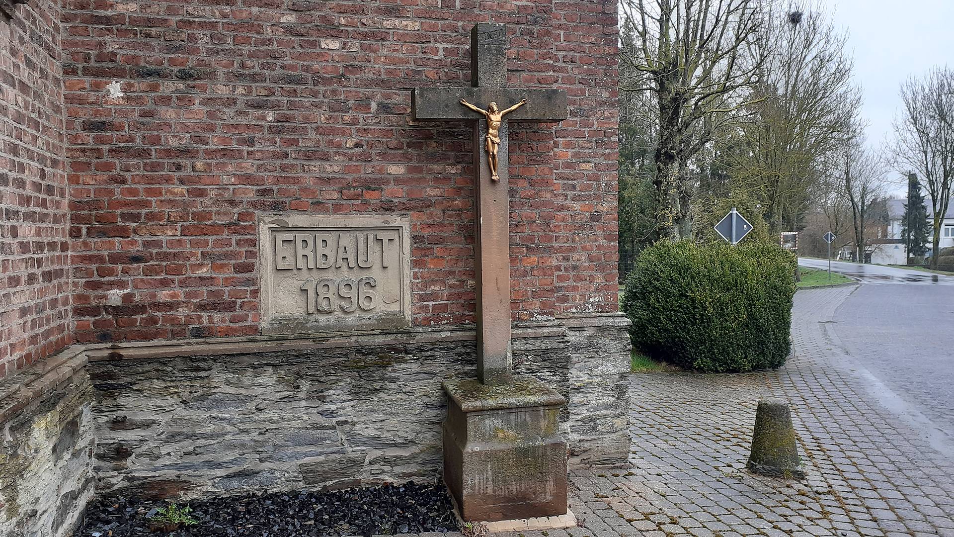Westseite der Pfarrkirche mit Jahreszahl der Grundsteinlegung und Balkenkreuz aus Sandstein (frühes 19. Jahrhundert)